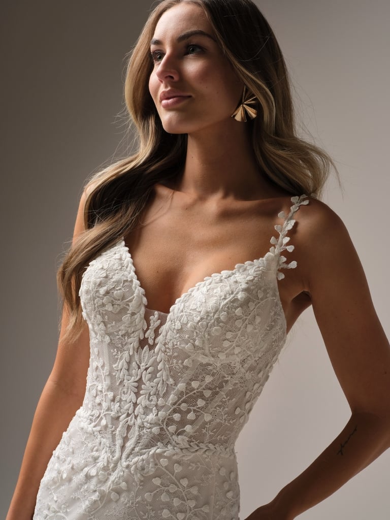 Wedding Dresses | The Isabella wedding gown, available in our curvy fit, is designed to celebrate your shape with confidence and elegance. This flattering fit-and-flare silhouette hugs in all the right places, while delicate floral lace cascades from bodice to hem for a romantic finish. A plunging neckline with illusion straps adds modern allure, and the button-back detail with a flowing train ensures you’ll turn heads from every angle. Perfect for the bride who wants classic beauty with a contemporary twis