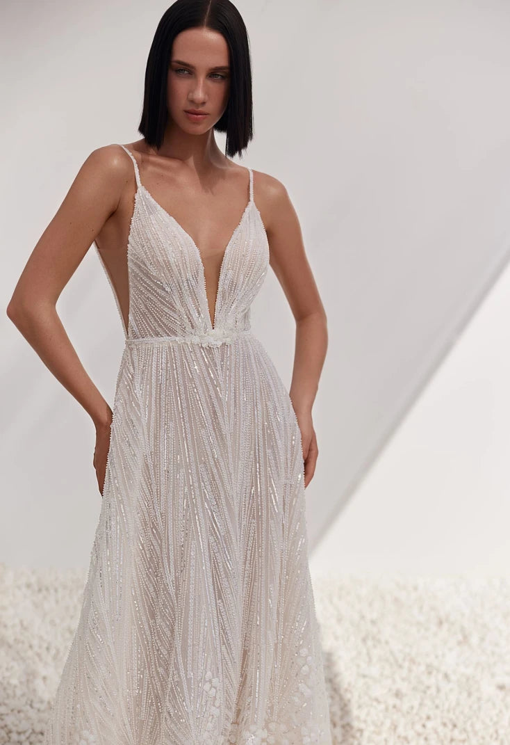 Woman wearing a white beaded dress against a neutral background