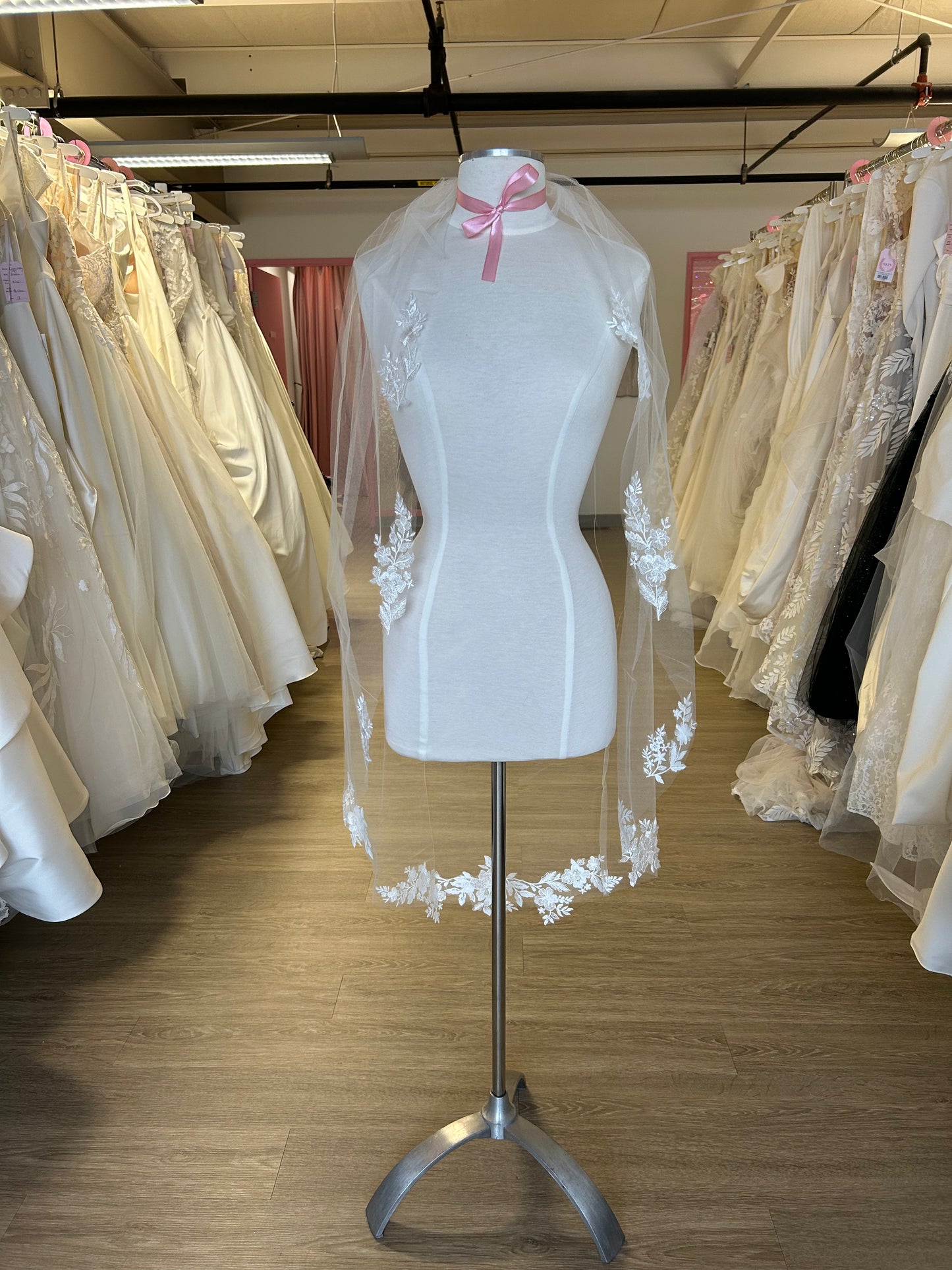 Mannequin wearing a lace veil in a room with wedding dresses