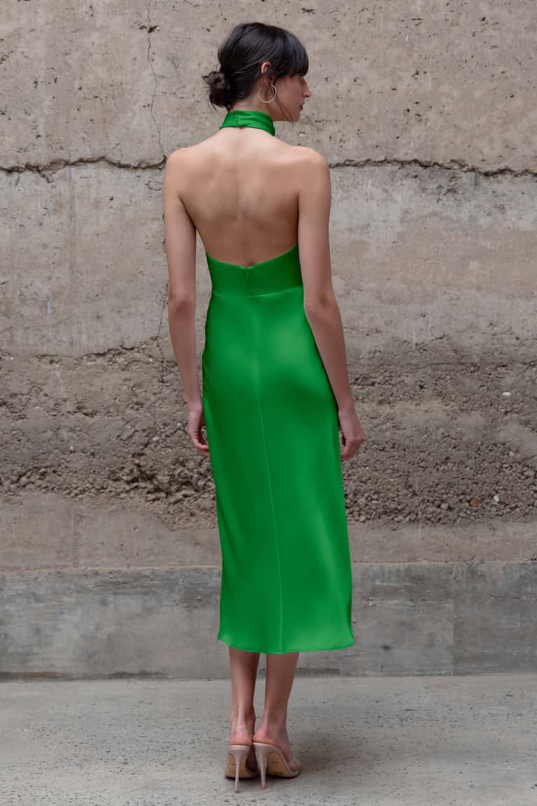 Woman wearing a green dress against a textured wall.