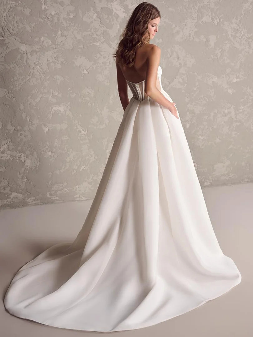 White wedding dress with a long train on a neutral background