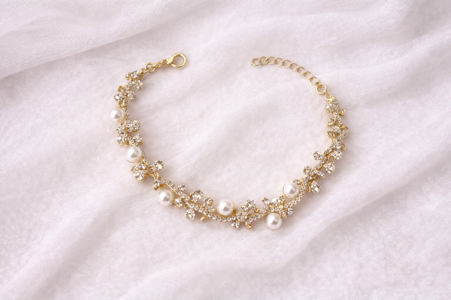 Gold bracelet with pearls on a light fabric background