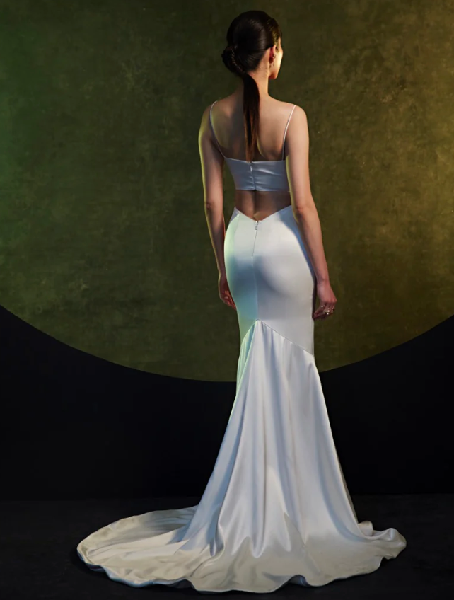 Model wearing Venus by Theia Couture - a fitted v-neck wedding dress with a slit, - full body back view
