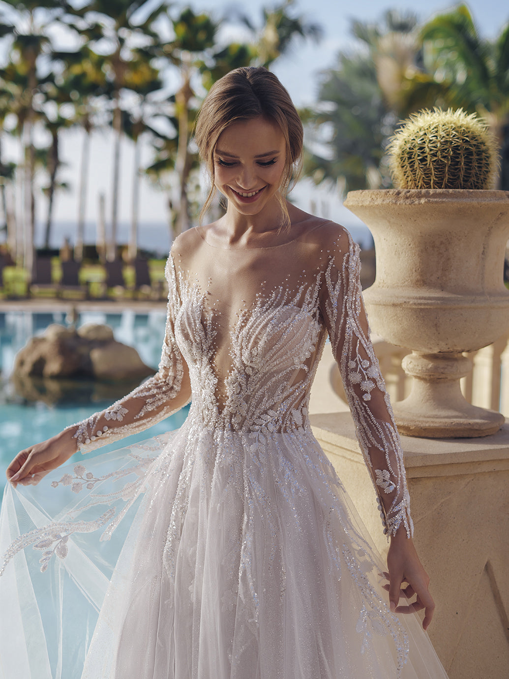 This geometric beaded lace A-line gown is a vision of bridal beauty, and its illusion long sleeves with beaded leafy lace give a mystical, enchanting vibe. The figure-flattering illusion lace bodice hugs the curves, while the flared glitter tulle and soft tulle skirt creates a sense of drama and romance, ensuring you make a lasting impression on your wedding day.