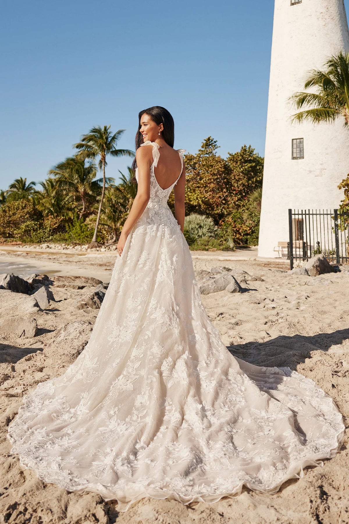 Back of the fairtytale whimsical a-line v-neck beaded tulle wedding dress with bow sleeves. The back is a low back v-back, shown on the beach.