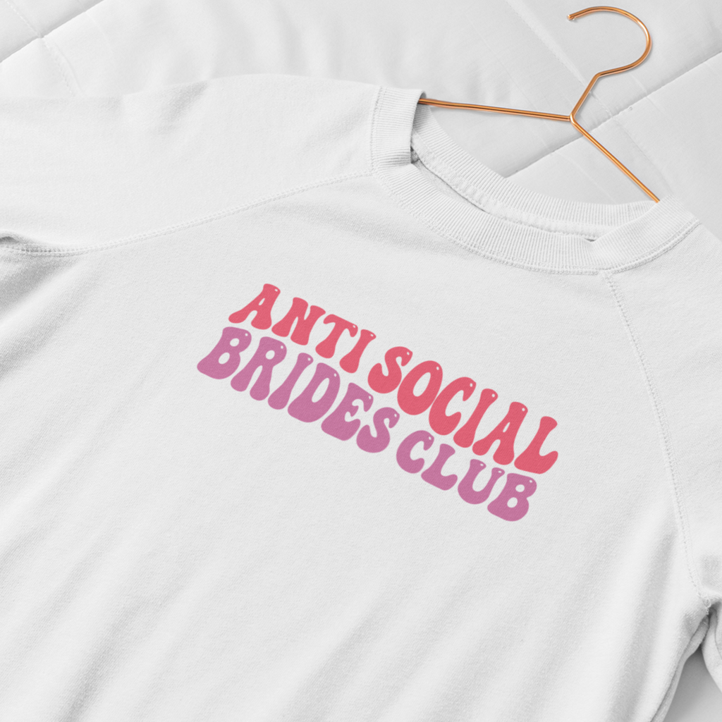 A white sweatshirt with "anti social brides club" written in pastel retro writing in the centre.
