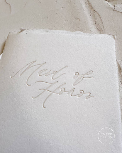 White vow book with silk ribbon and "maid of honor" pressed on the front