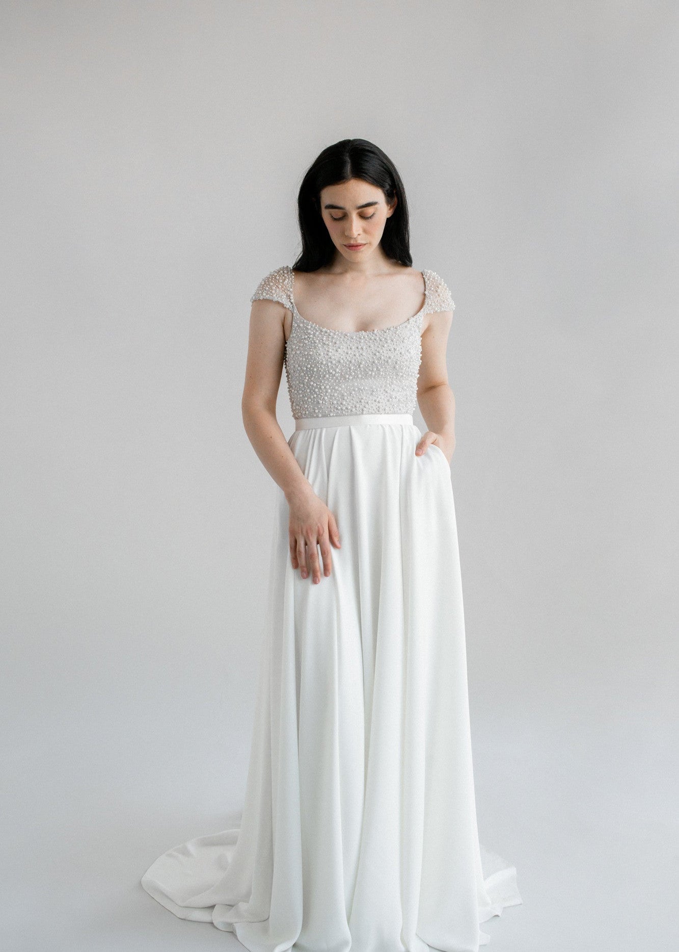 Kaley, a stunning flowing a-line wedding dress finished with a pearl bodice and cap sleeves - full body front view