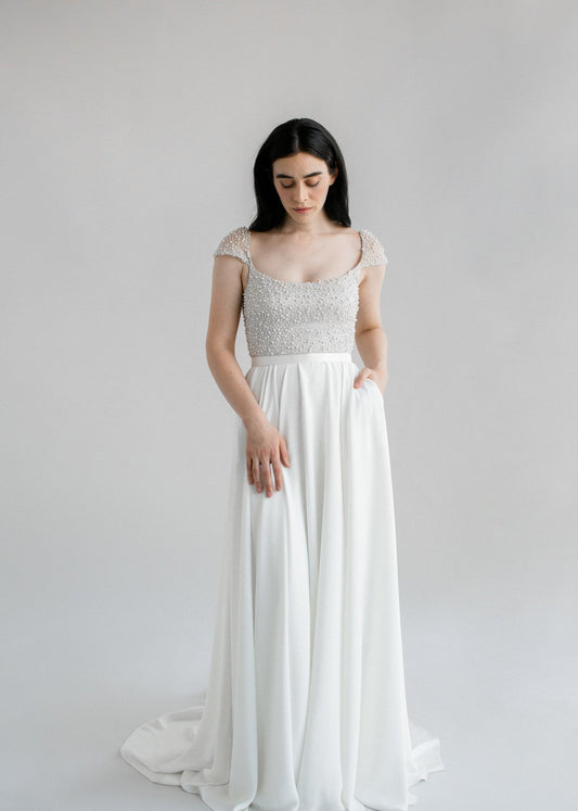 Kaley, a stunning flowing a-line wedding dress finished with a pearl bodice and cap sleeves - full body front view