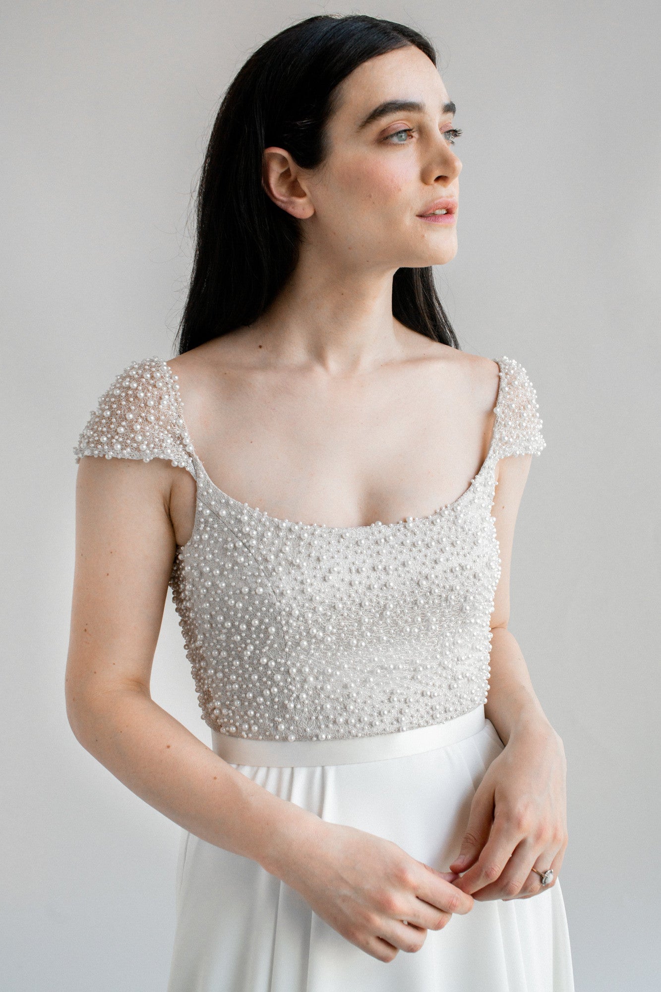 Kaley, a stunning flowing a-line wedding dress finished with a pearl bodice and cap sleeves - close up front view