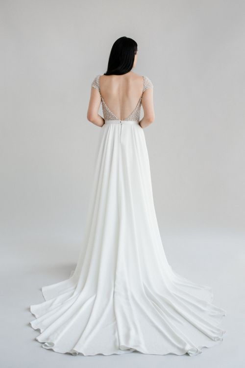 Kaley, a stunning flowing a-line wedding dress finished with a pearl bodice and cap sleeves- full body back view