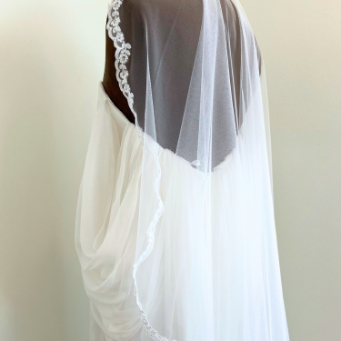 White wedding dress with a veil on a plain background
