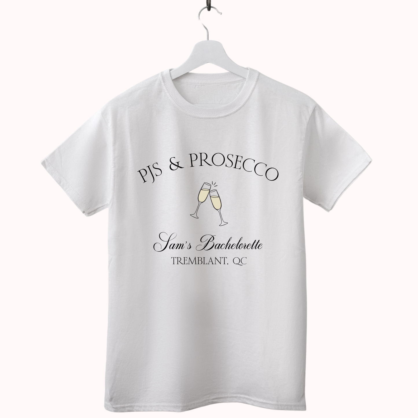 White t-shirt with 'PJs & Prosecco' text and champagne glass design on a hanger against a white background