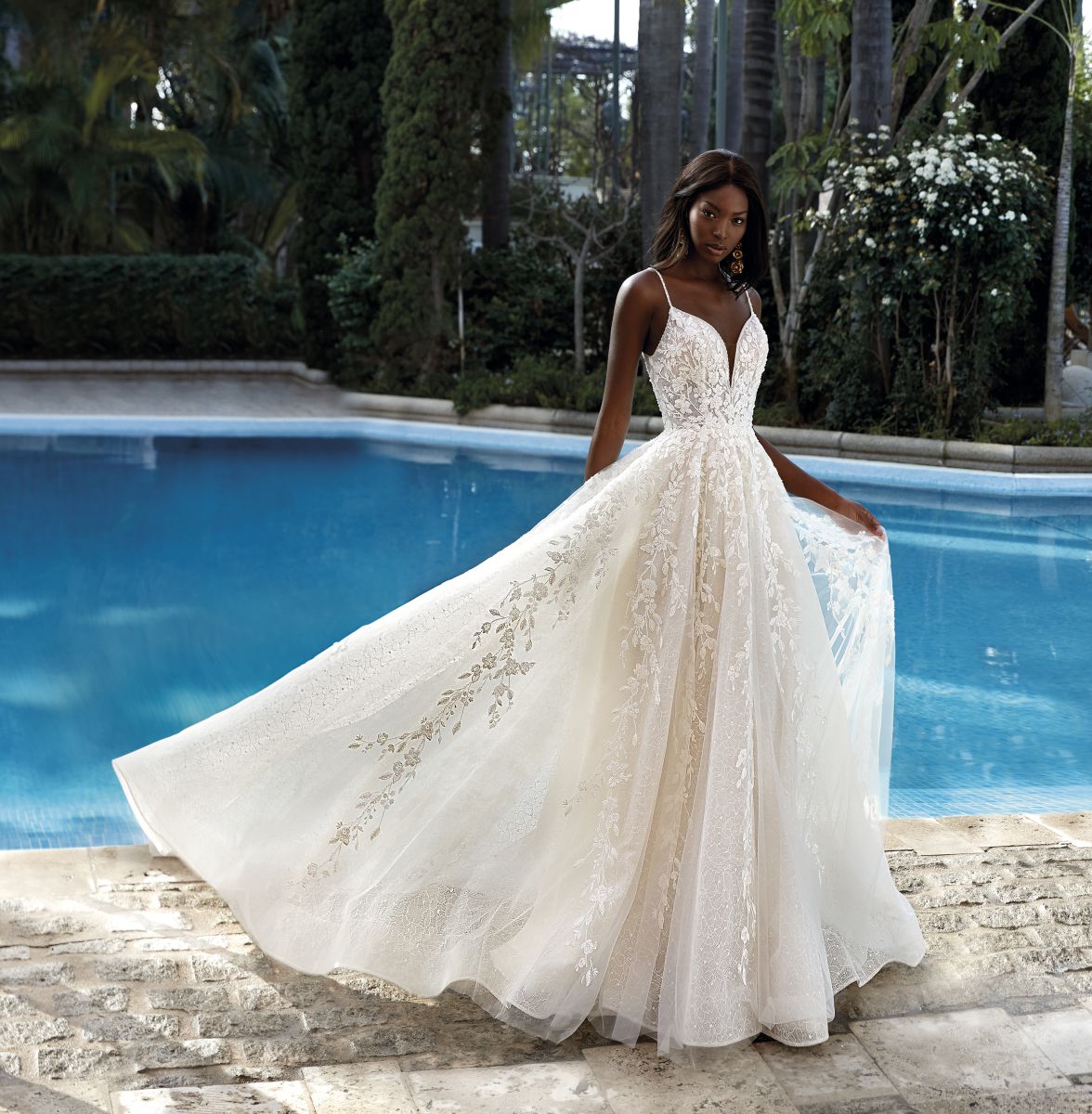 A woman wearing a sleeveless ivory wedding gown with floral lace embroidery and a full flowing skirt, 1199 by Demetrios. Style available at NKIN Bridal Ottawa