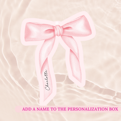 Pink bow with a name tag on a soft pink background