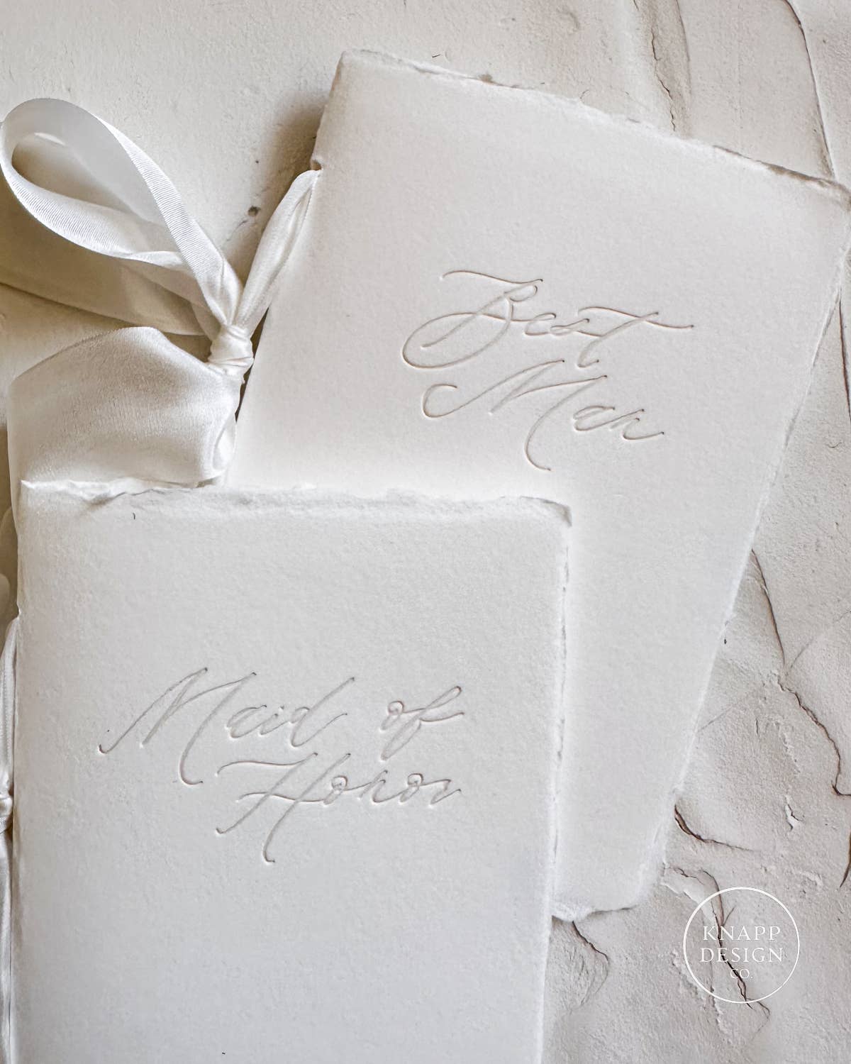 White vow book with silk ribbon and "maid of honor" pressed on the front and best man matching