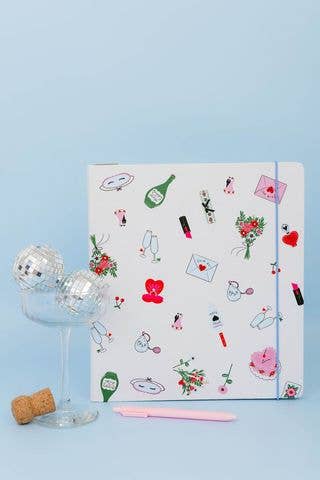 White kate spade planner with small wedding graphics on a blue backdrop