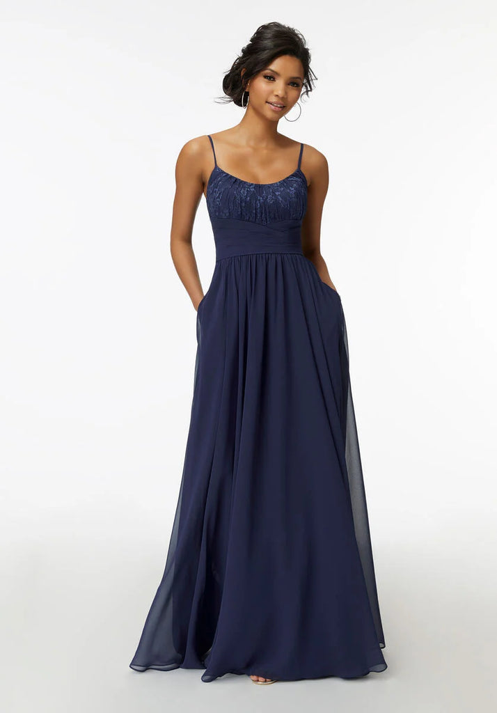 Bridesmaid dress with a sweet Chantilly Lace bodice, scoop neckline and chiffon skirt featuring pockets and a ruched waist detail that ties to a sash in back. Shown in Sapphire.
