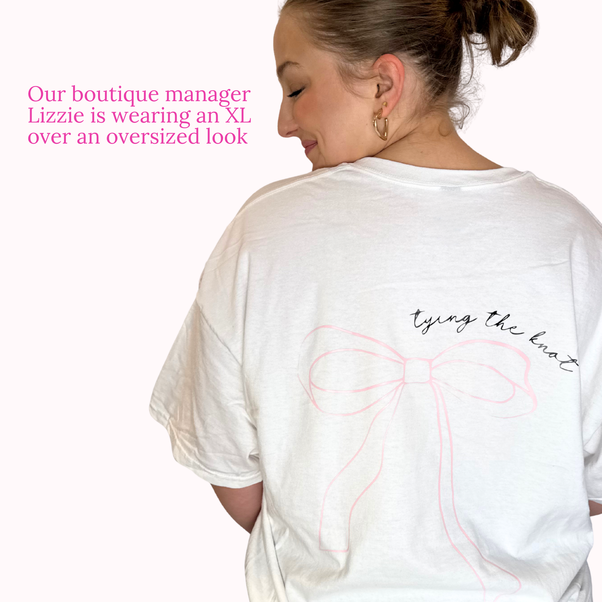 Person wearing a white oversized t-shirt with a bow design and text on a plain background