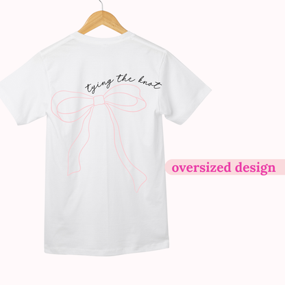 White t-shirt with oversized bow design and text on a hanger