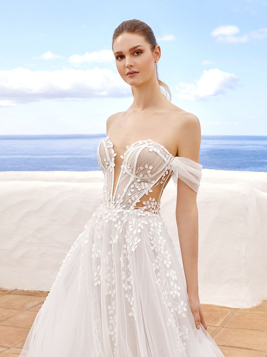 Leaving us in a trance, CLAIRE is perfect for our dreamy romantics. This ethereal A-line beauty showcases a plunging sweetheart neckline with intricate 3D floral motifs and embroidered lace atop sparkly glitter tulle fabric. The romantic exposed corset boning, illusion side cut-outs, and off-the-shoulder tulle straps tie together to create an enchanting bridal look. The lovely lace is carefully placed along the corset-style back and peek-a-boo slit, trickling down into a soft and sparkly tulle skirt.

