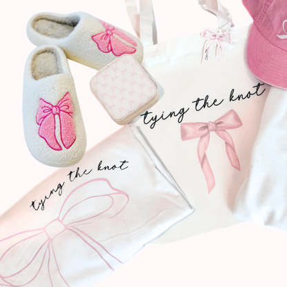 Slippers, tote bag, and cap with pink bows and 'tying the knot' text on a white background