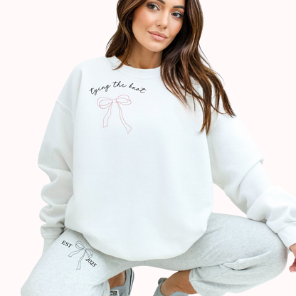 Woman wearing a white sweatshirt with text and graphics, sitting on a white background