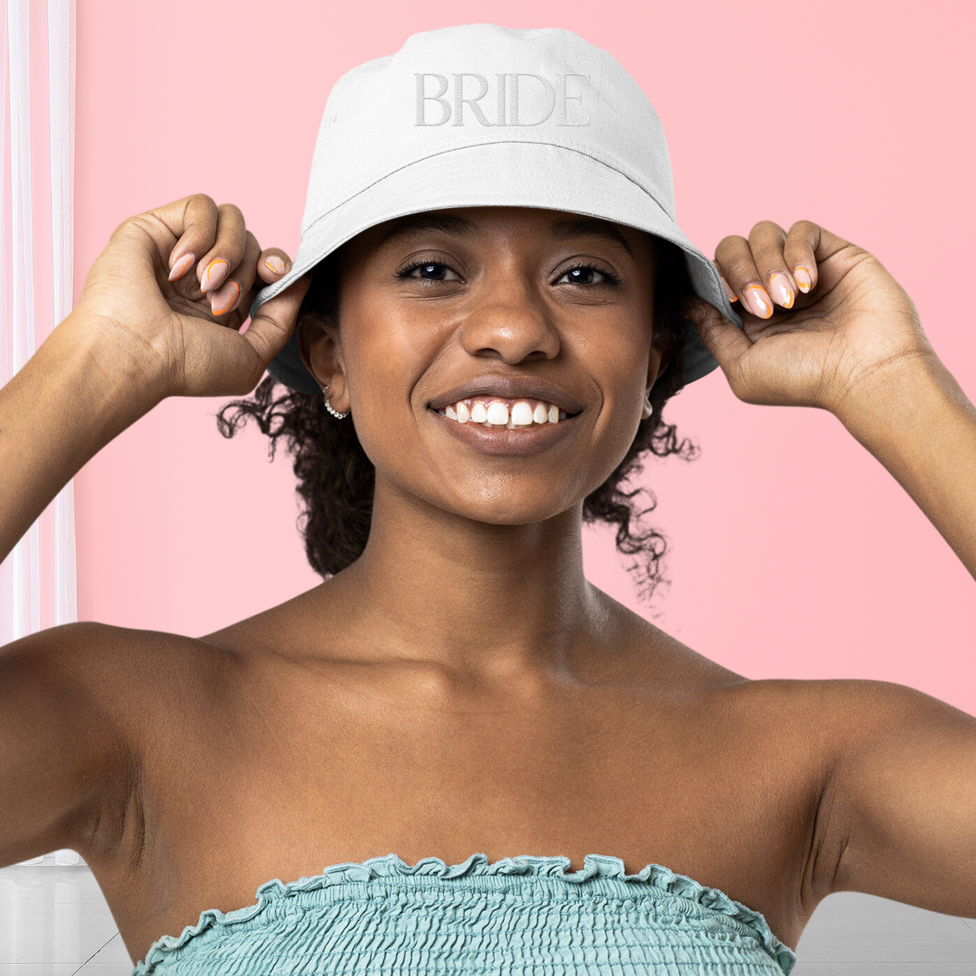 Young woman wearing white hat "bride" embroidered on the front