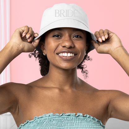 Young woman wearing white hat "bride" embroidered on the front
