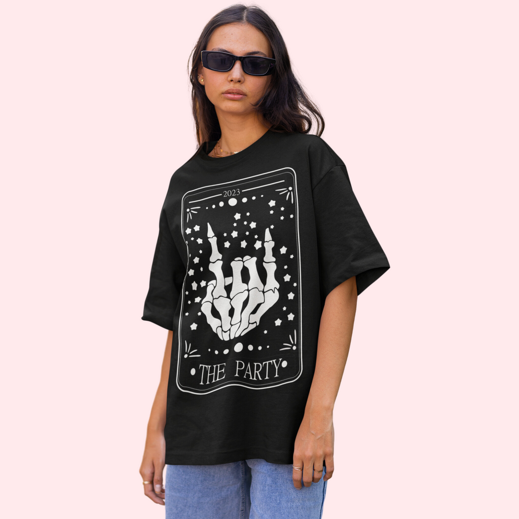 A young woman wearing a black shirt with "the party" in a tarot card and a skeleton hand 