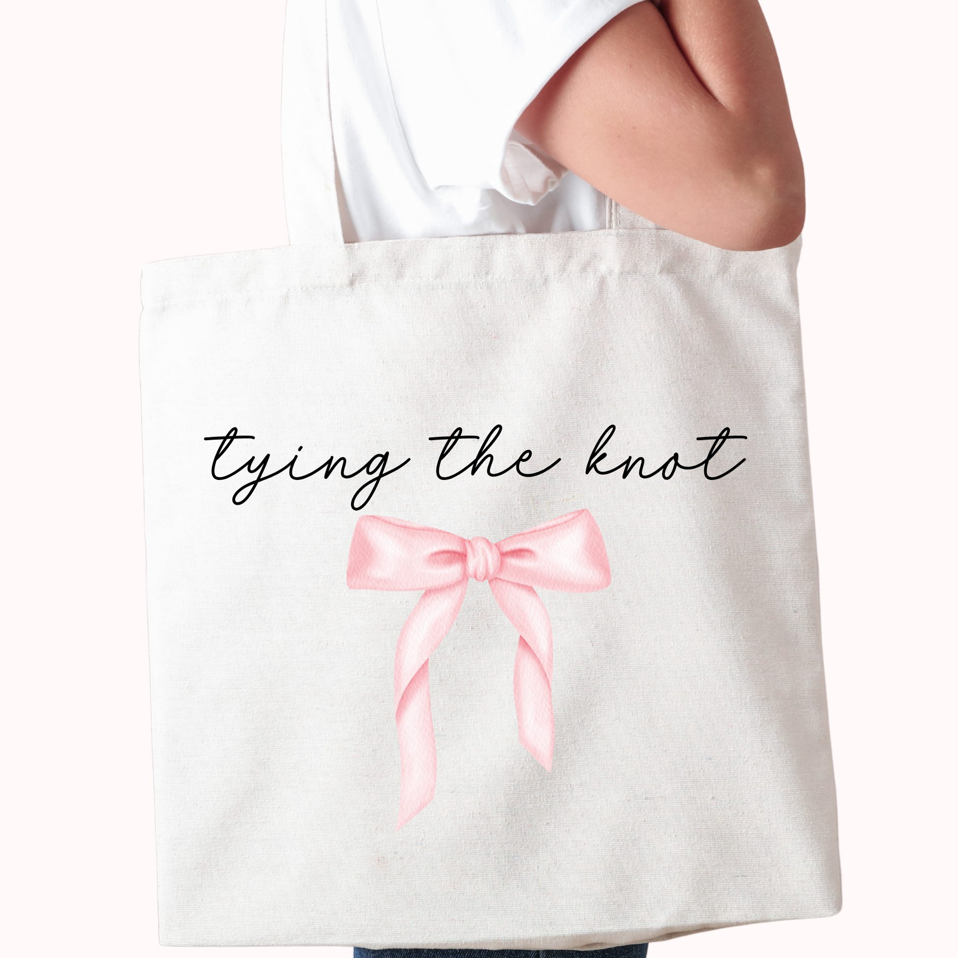 Tote bag with a pink bow and 'tying the knot' text on a white background