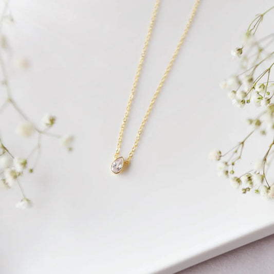 Dainty bezel necklace on a gold chain on a white background