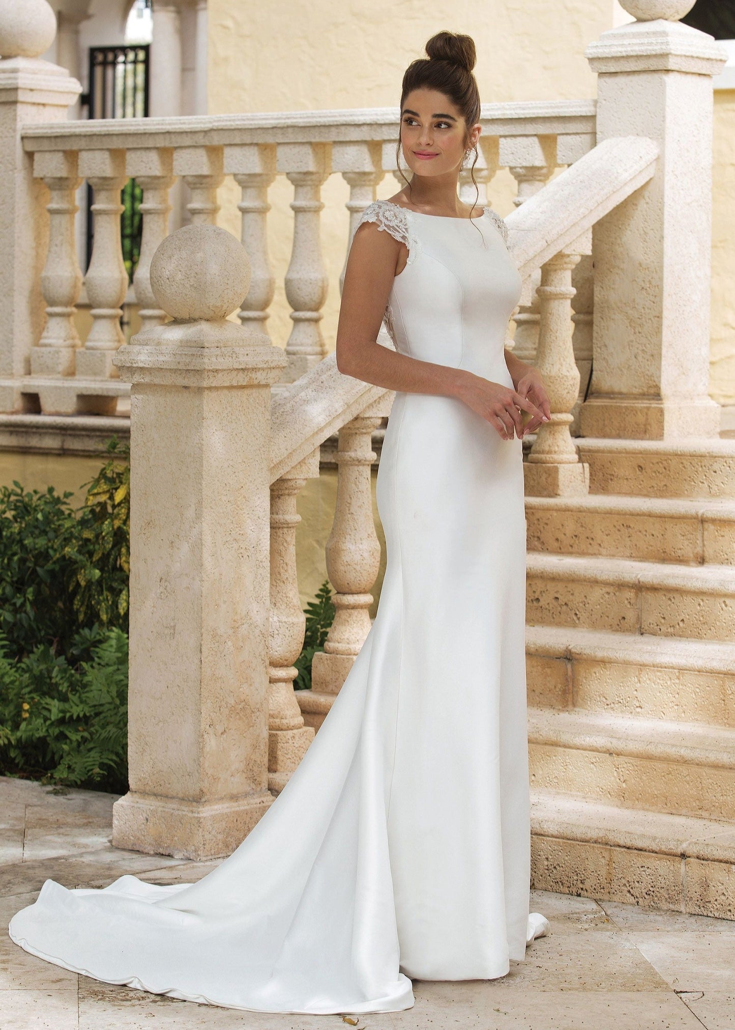 Woman wearing a high neck sheath wedding dress with lace cap sleeves