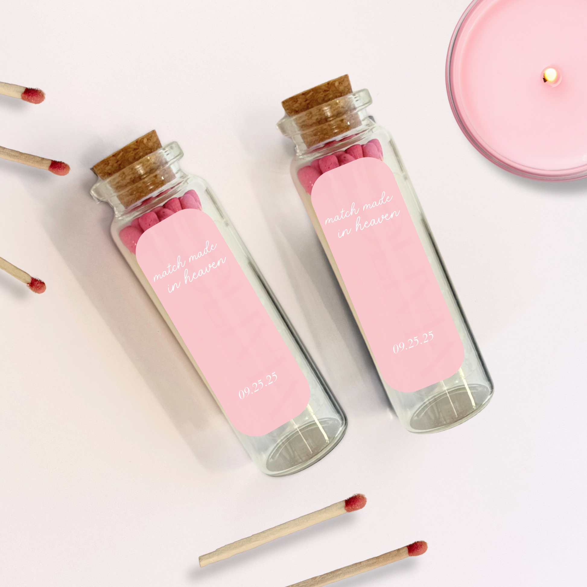 Two glass jars with pink labels and matches on a light background