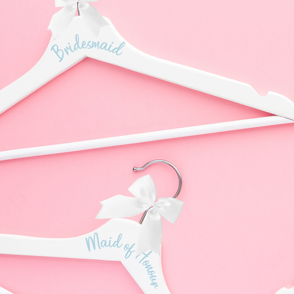 2 white hangers - one with "bridesmaid" and the other "maid of honour" written in blue