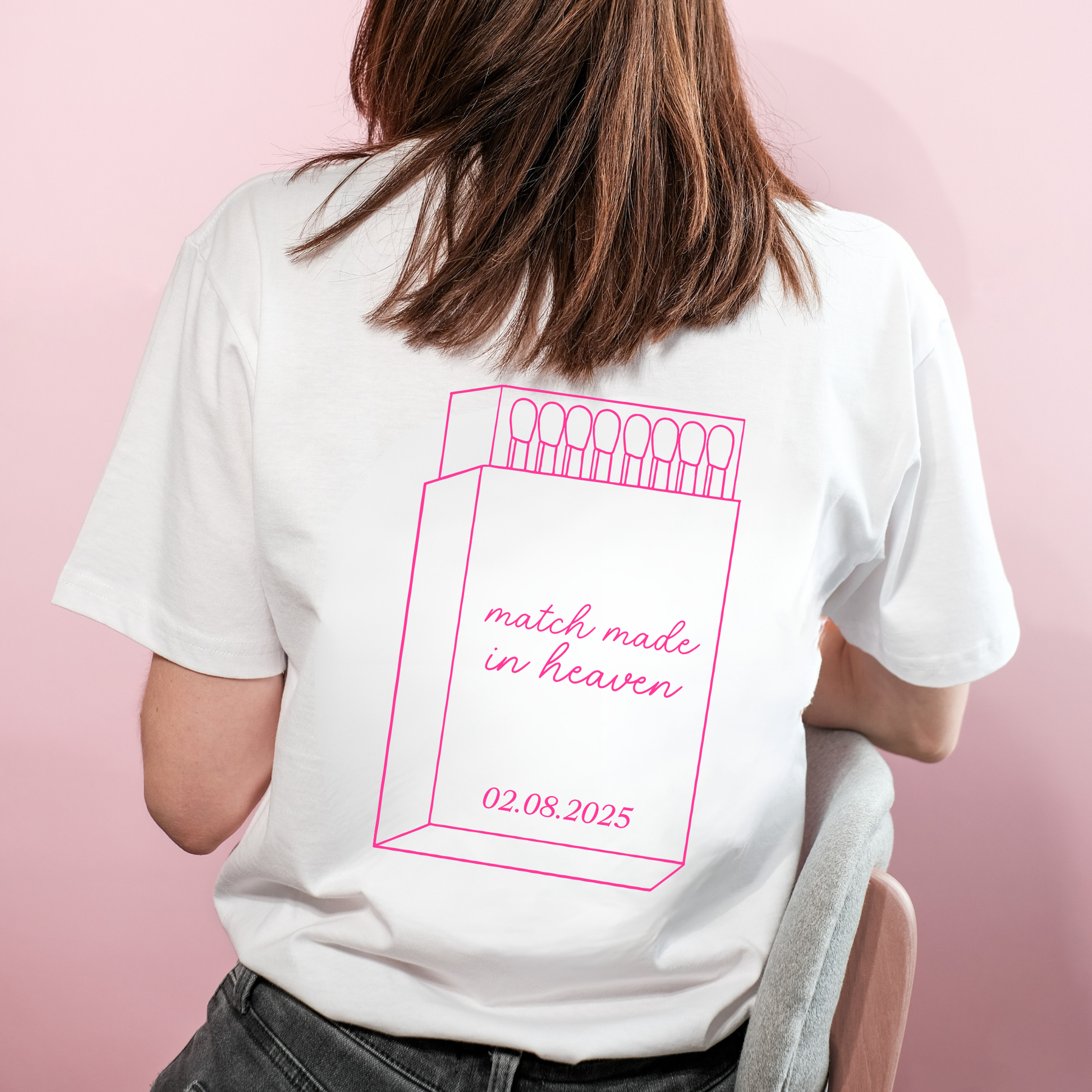 Person wearing a white t-shirt with pink graphic and text on a pink background