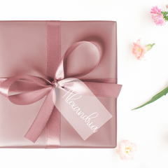 A pink wrapped gift box with acrylic tag and 