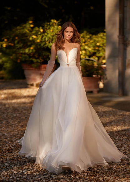Woman wearring wedding dress - a-line with a cat eye/sweetheart neckline, full body front view