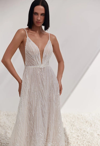 Woman wearing a white beaded dress against a neutral background