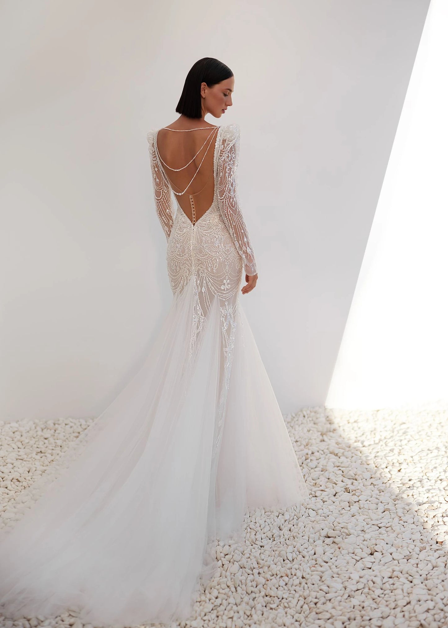 Woman wearing a white wedding dress with intricate detailing on a white background