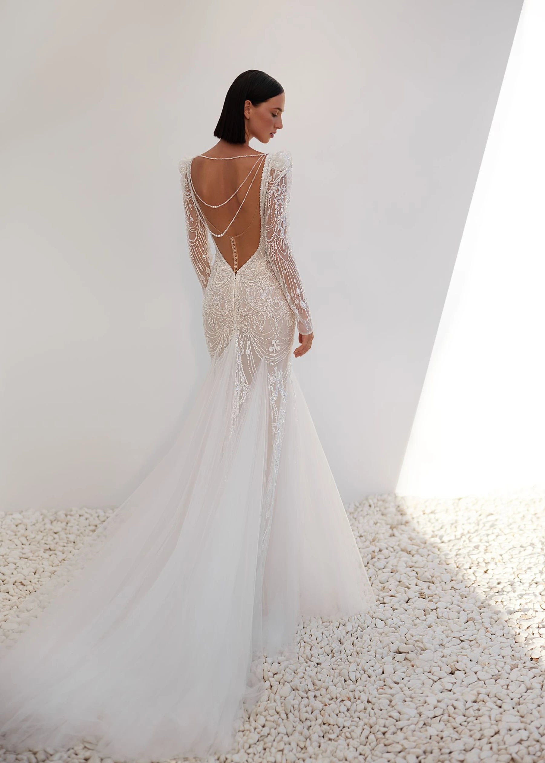 Woman wearing a white wedding dress with intricate detailing on a white background