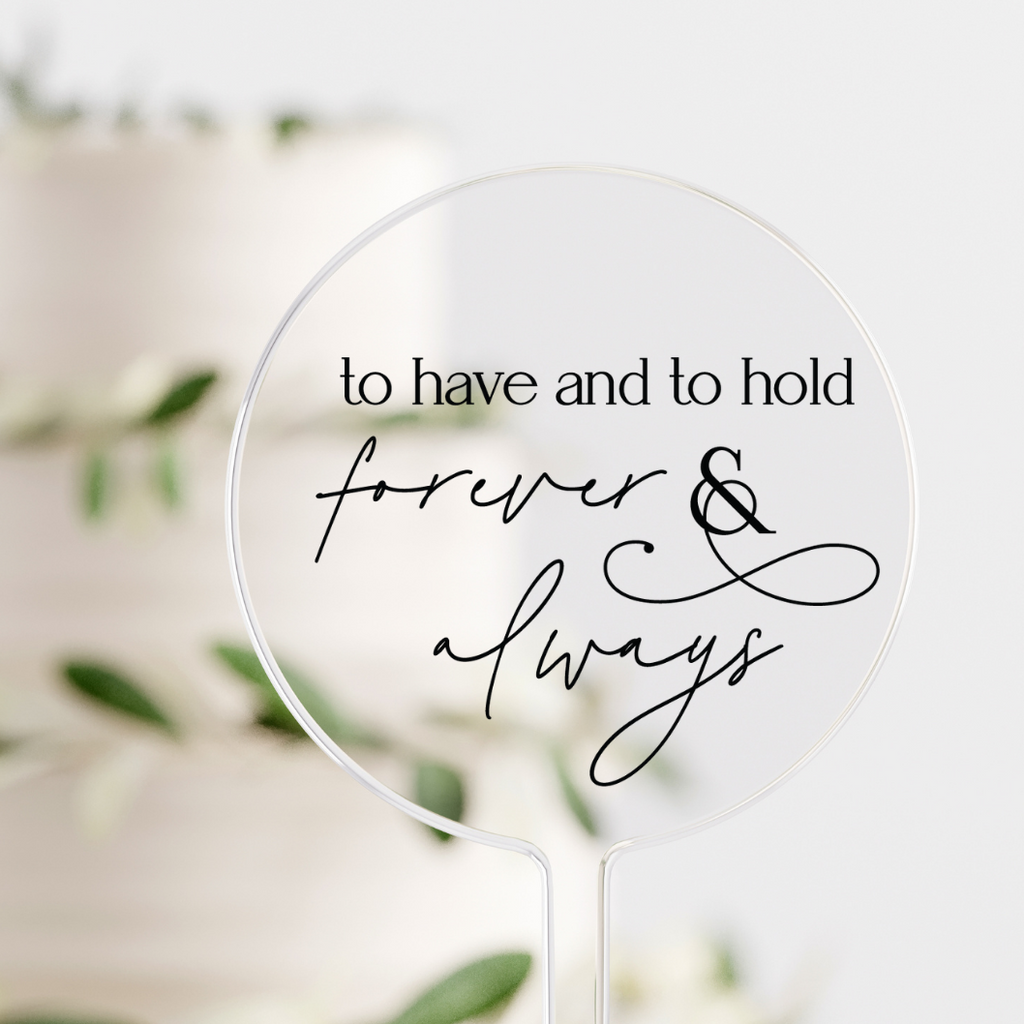 Circular clear cake topper with "to have and to hold forever & always" written in black
