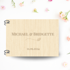 A natural wood hardcover guest book on a pink, floral background. 