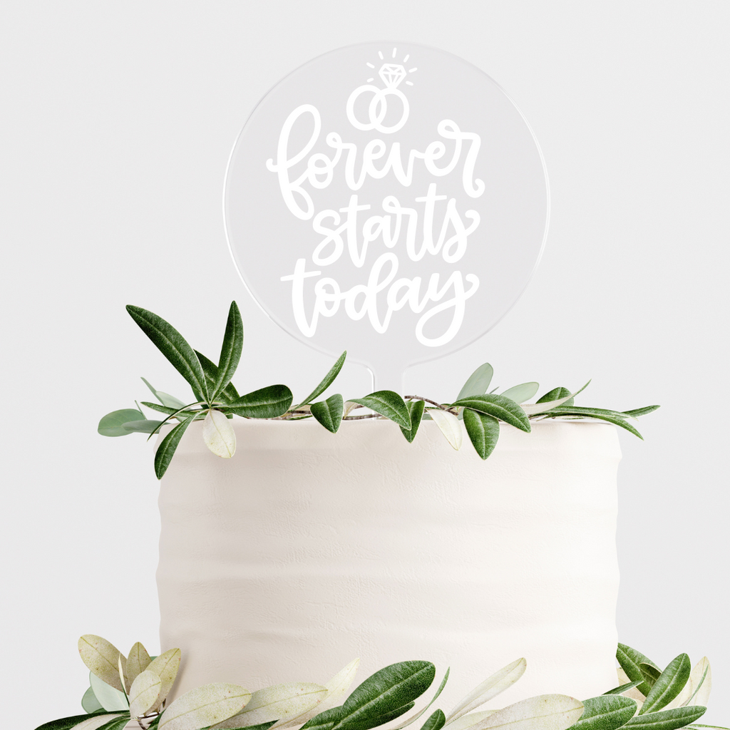 Circular clear cake topper with "forever starts today" written in white