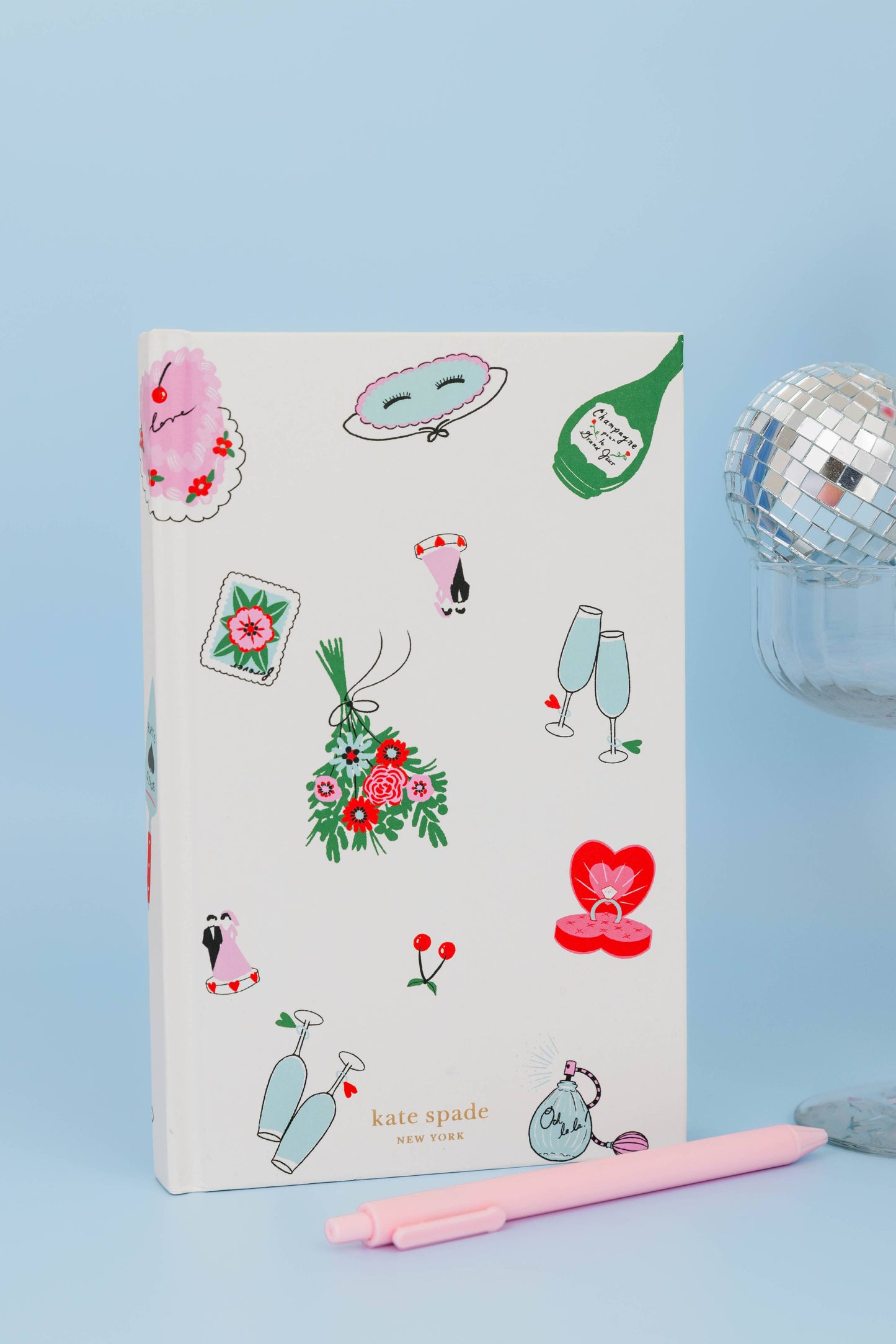 White kate spade notebook with wedding graphics on a blue backdrop