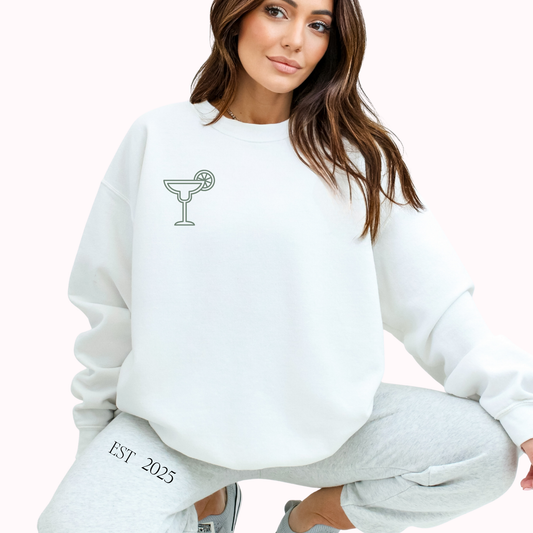 Woman wearing a white sweatshirt with a graphic design and text, sitting on a white background