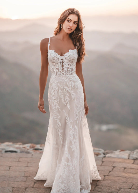 Woman in a white lace wedding dress standing on a mountain with a scenic background