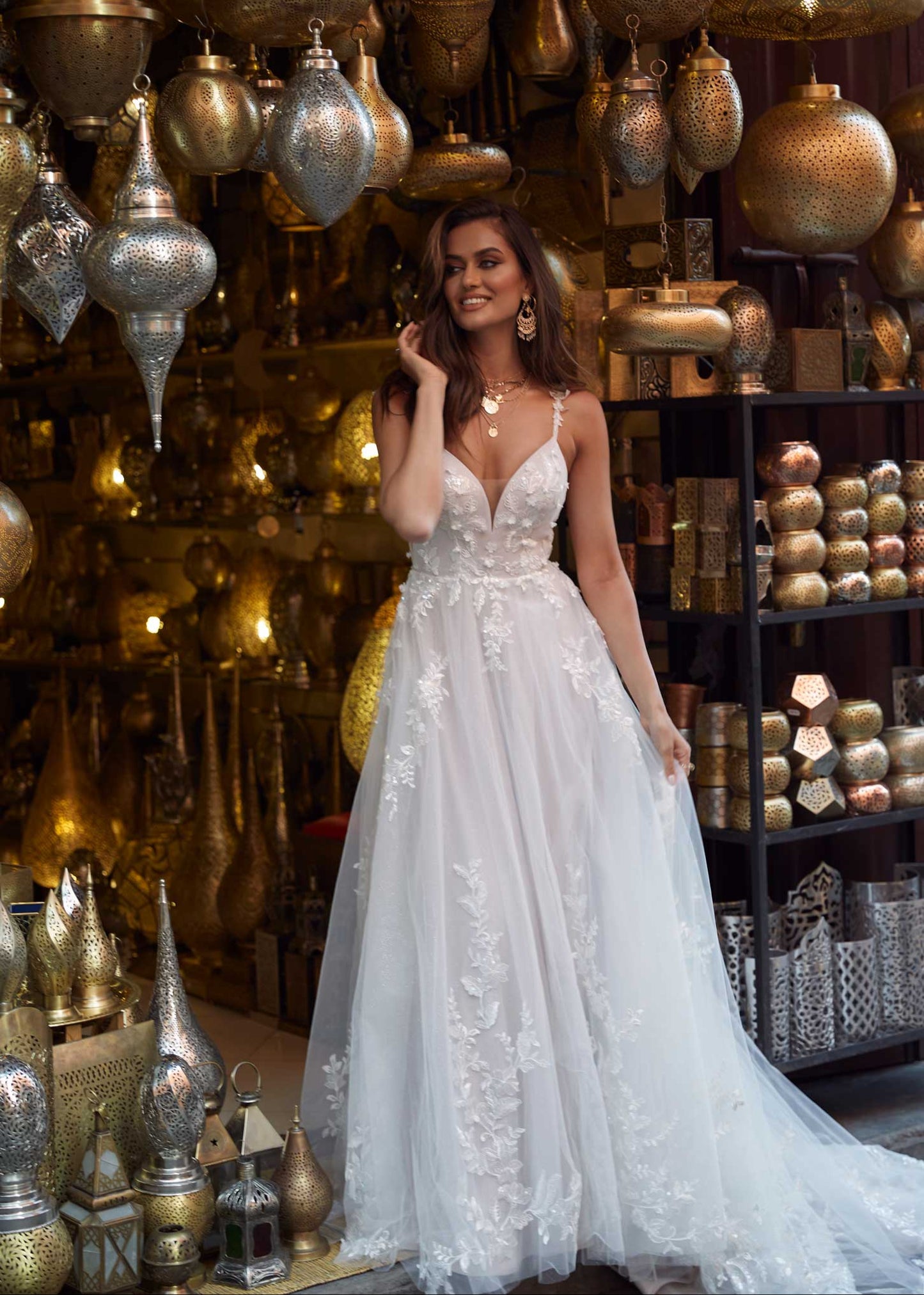 Woman wearing Aria - a v-neck a line wedding dress with florals all the way down and thin spaghetti straps, full body front view