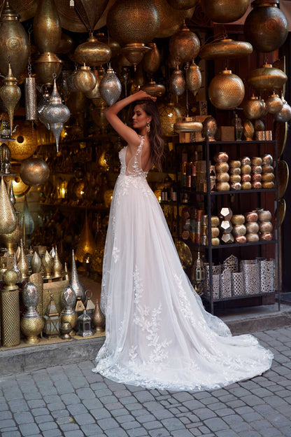 Woman wearing Aria - a v-neck a line wedding dress with florals all the way down and thin spaghetti straps, back view