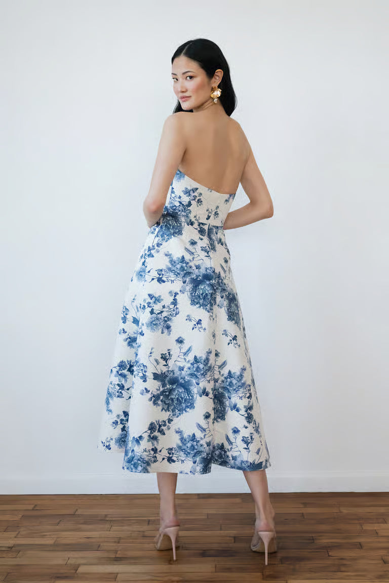 Woman wearing a strapless floral dress with blue flowers on a white background